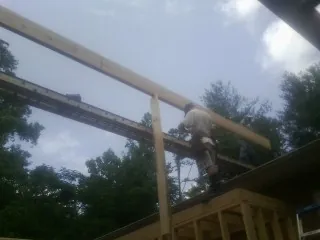 Carpenter setting a ridge beam over a new addition frame — Ice Dam Removal by Roofing Brothers in Absaraka
