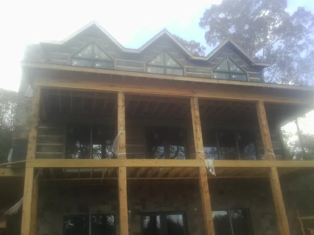 Dormers and porch framing on a large log home under construction — Roof Coating work by our crew in Absaraka