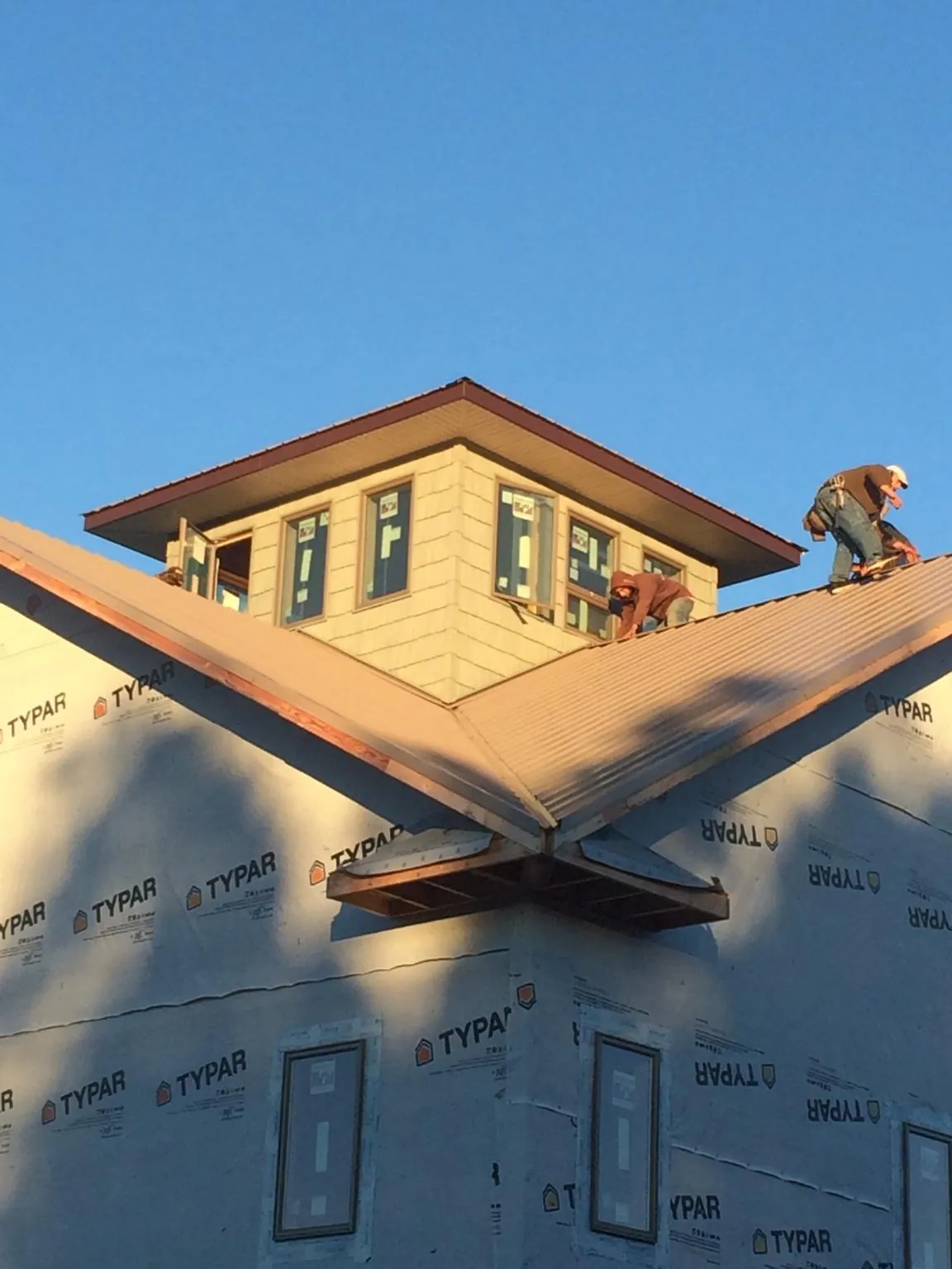 Roofers working around a rooftop cupola on a new metal roof at sunset — Roof Waterproofing in Absaraka by Roofing Brothers